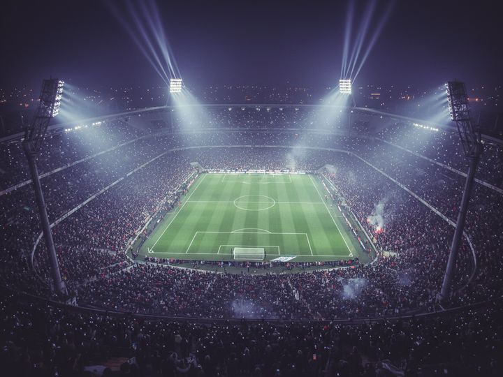 A packed football stadium at night seen from high in the stands