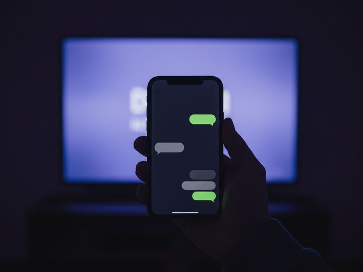 A hand holding a phone showing a messaging conversation